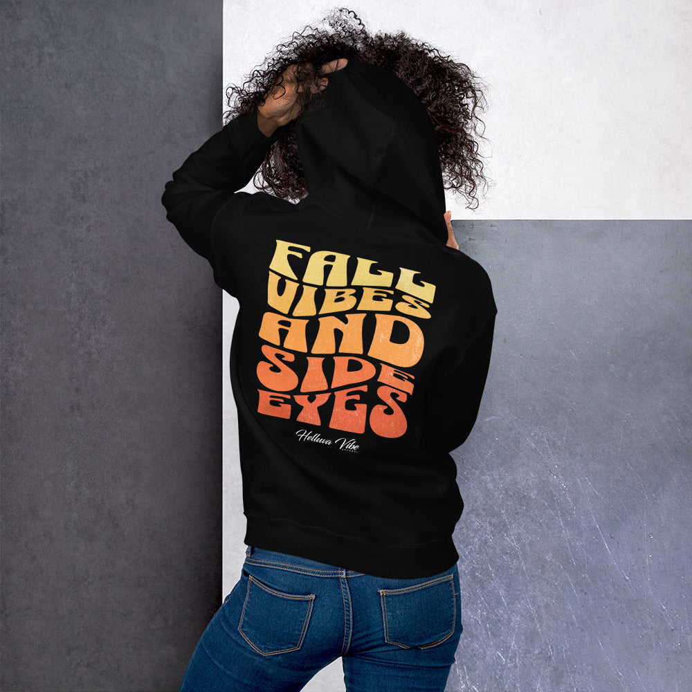 Person wearing a black hoodie with 'Fall Vibes and Side Eyes' text on the back, standing against a gray wall.